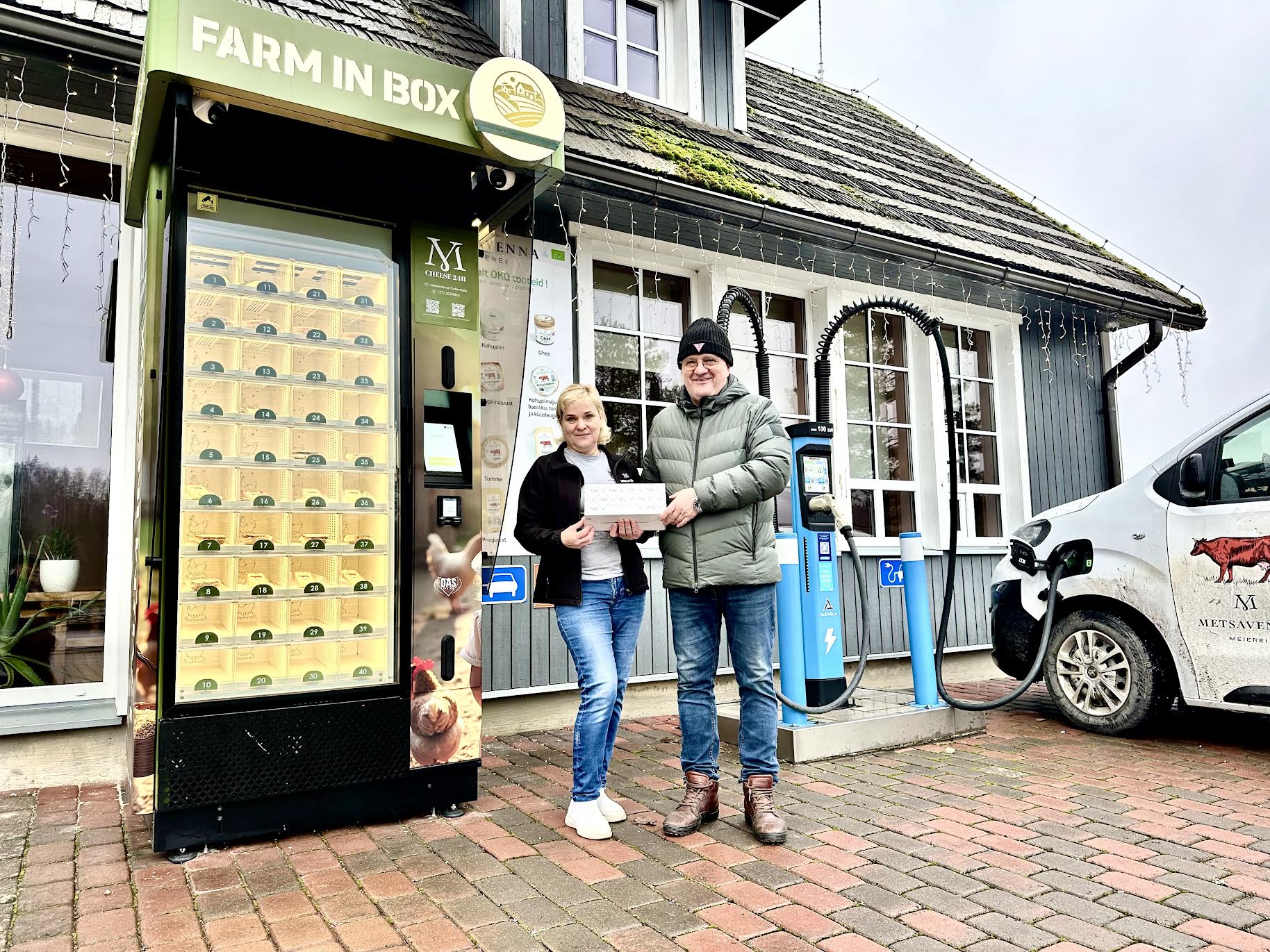 Metsavenna talu peremees Meelis Mõttus ja pikaaegne müüja Ruth Kuuba ööpäev ringi töötava müügiautomaadi ees. Nad hoiavad käes peatselt müügile tulevat kvaliteetjuustude ja sõira pakendit, kus kuus juustu ja sõir. Müügiautomaat töötab miinus 25 ja kuni 60 kraadi vahemikus. FOTOD: Kalev Annom